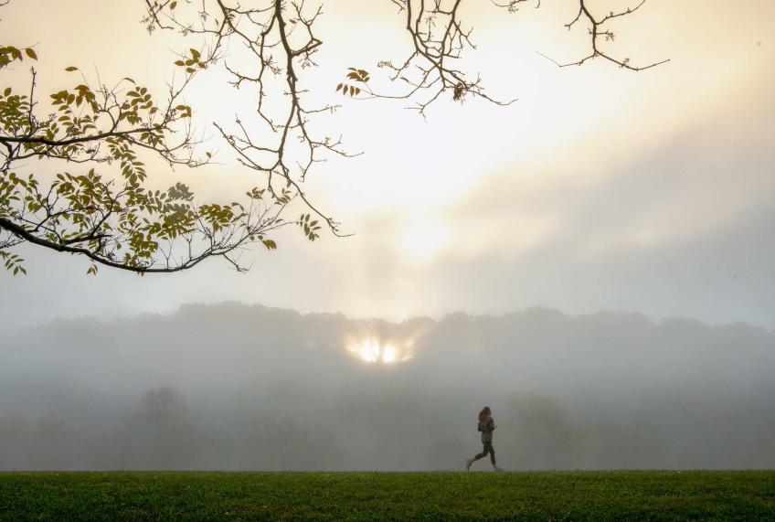 A lone runner on the Athens bike path amongst a foggy sunrise