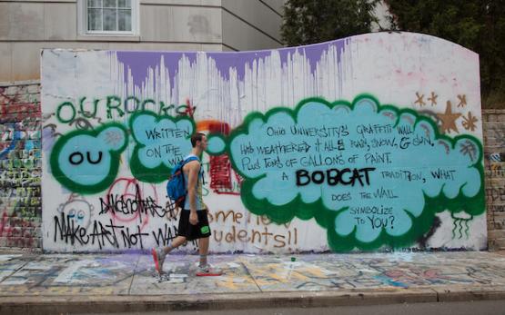 A student walks by in front of the graffiti wall, which is covered in different bright designs