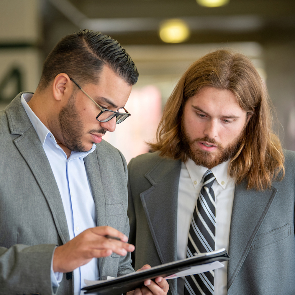 two men in suits looking at tablet