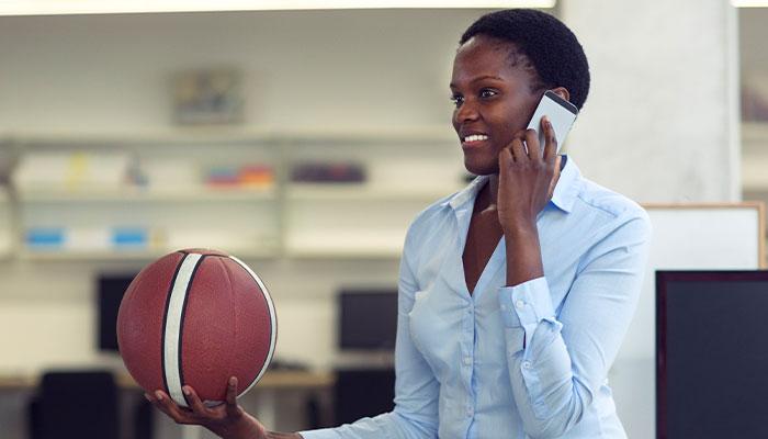 Woman on phone and holding basketball
