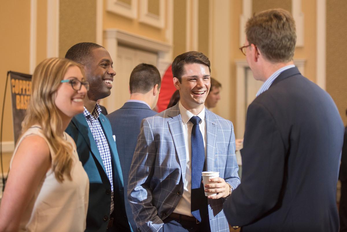 Students talk to a professor at an event.