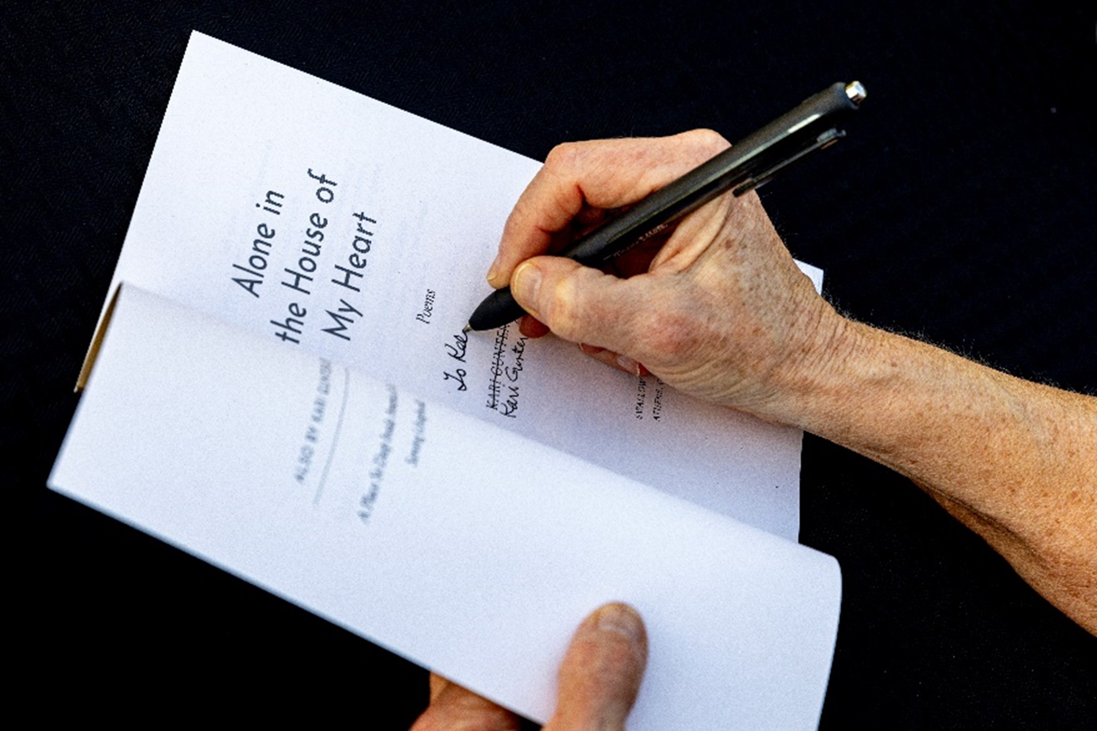 Photo of Kari Gunter-Seymour's hands signing a copy of Alone in the House of my Heart