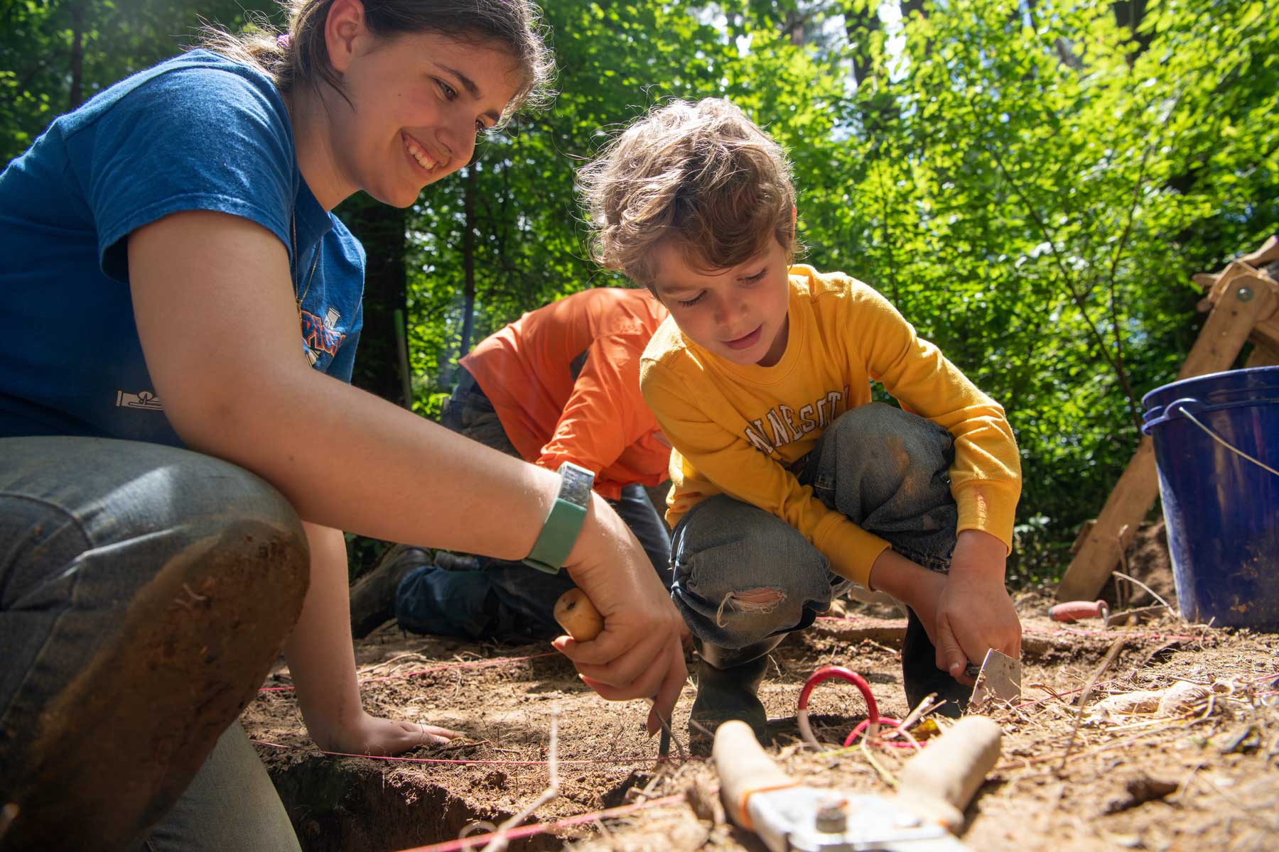 A student and young child dig in Wayne Nation Forest for archaeological specimen
