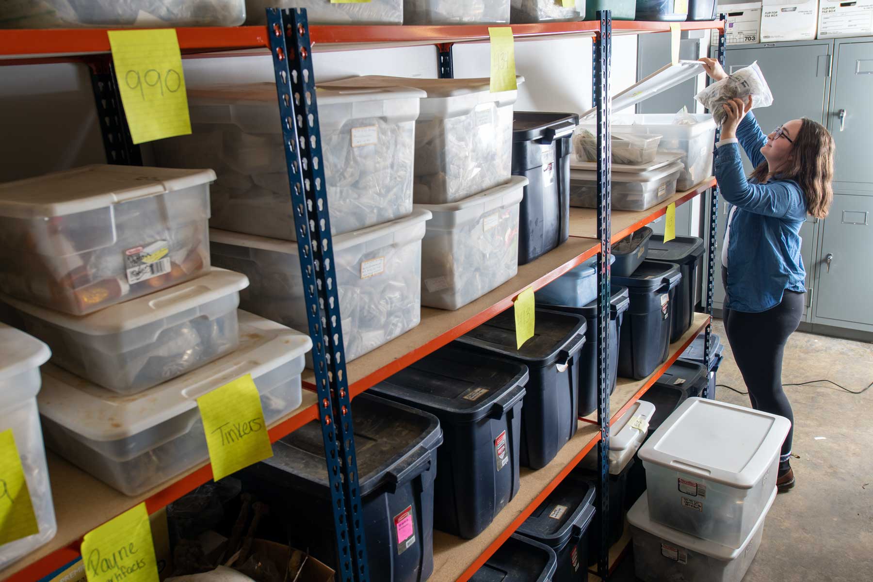 A student accessses stacks of boxes filled with categorized archaeological specimens