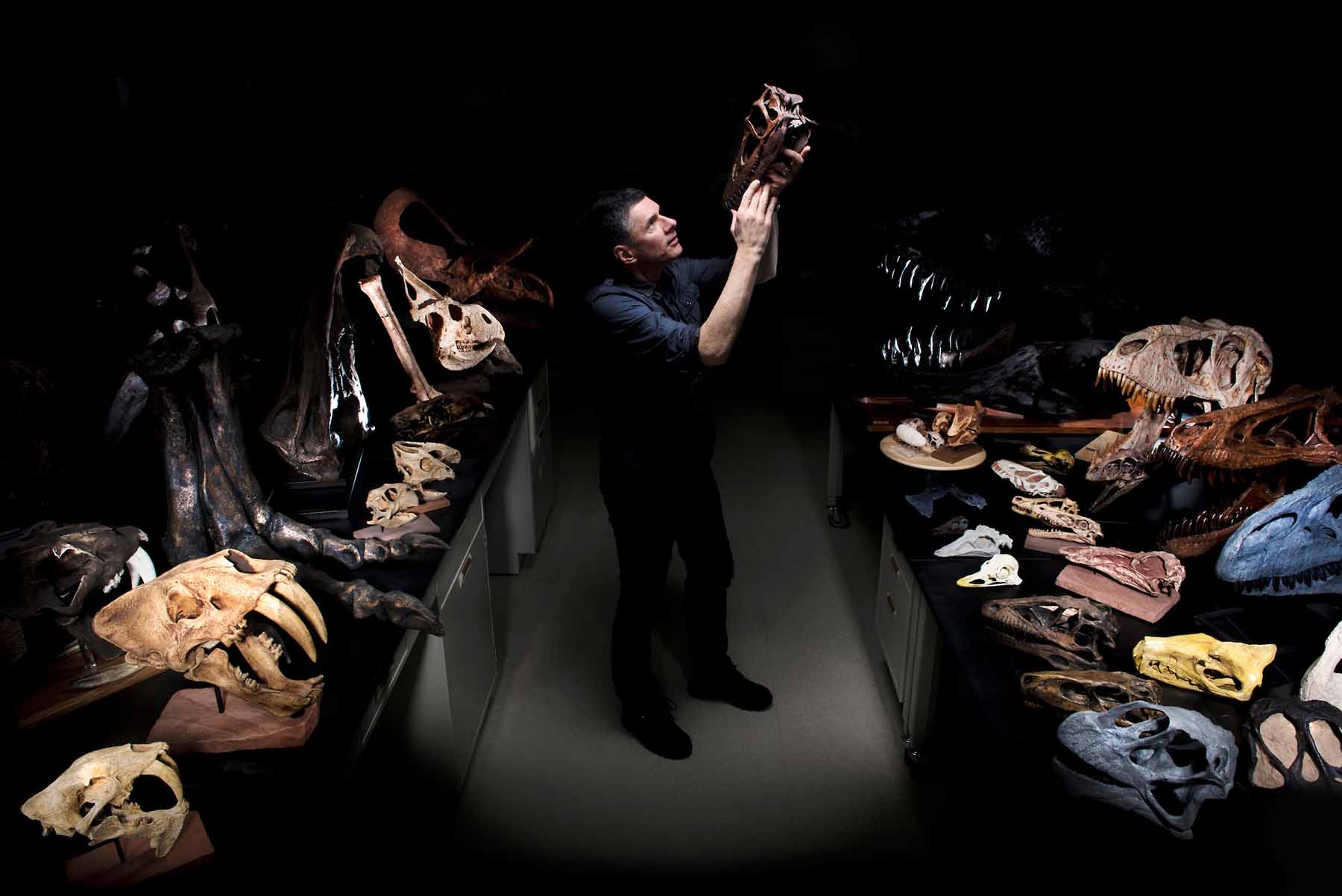 Professor Larry Witmer admiring prehistoric skeletons in a dimly lit room
