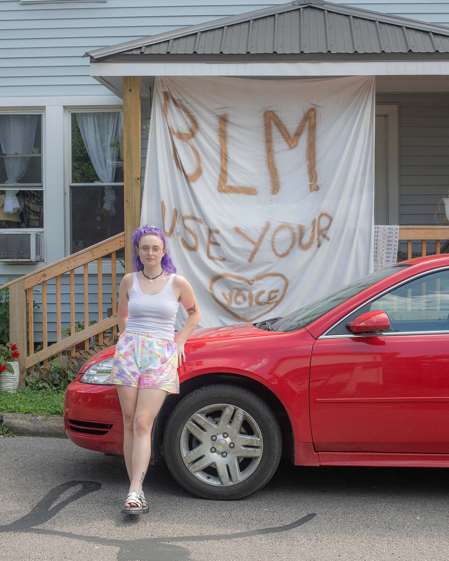 A student poses outside of her off-campus residence and its social justice banner