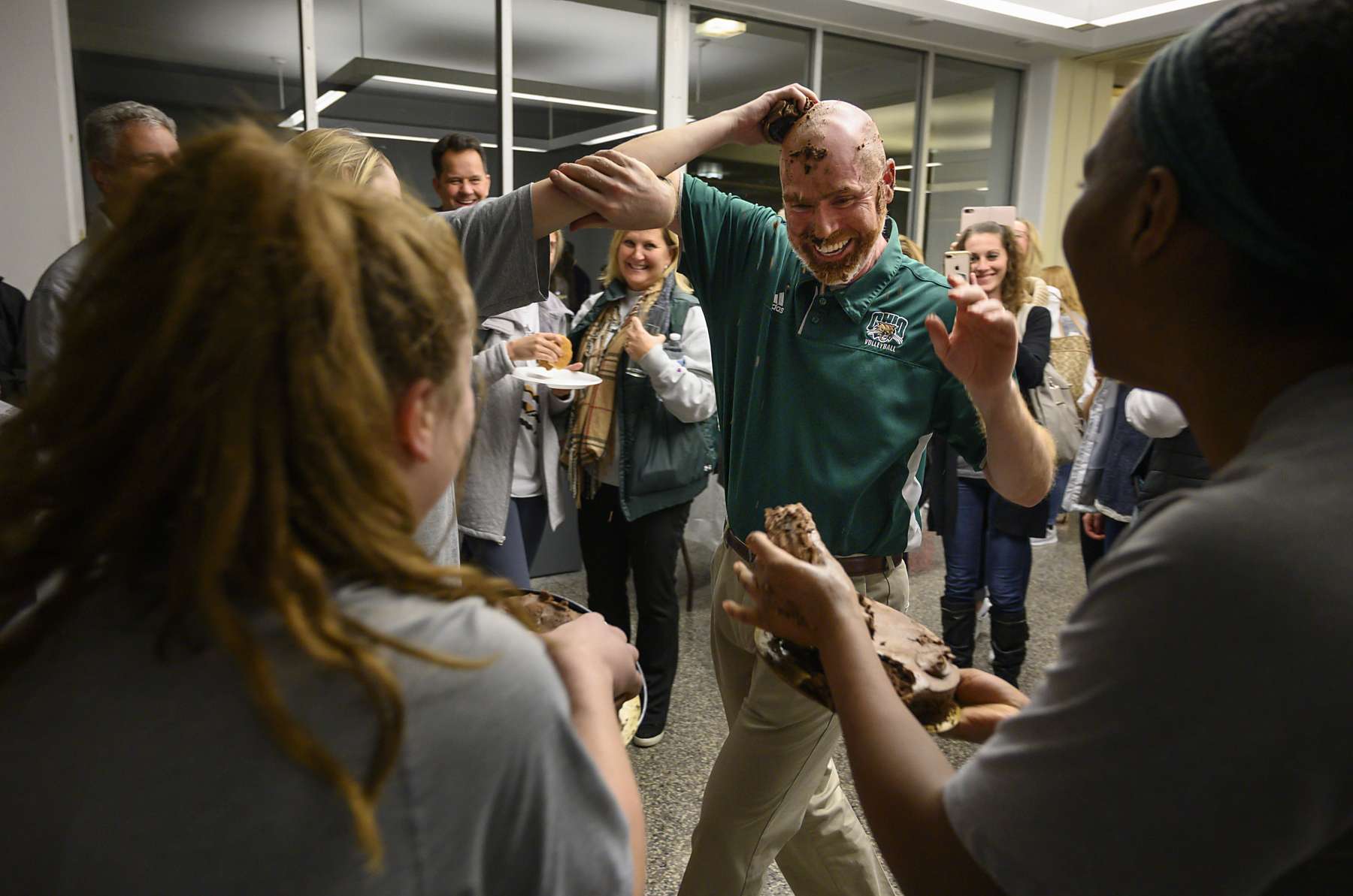 Ohio University volleyball coach, Deane Webb, smiles as his team surrounds him in celebration of senior game night