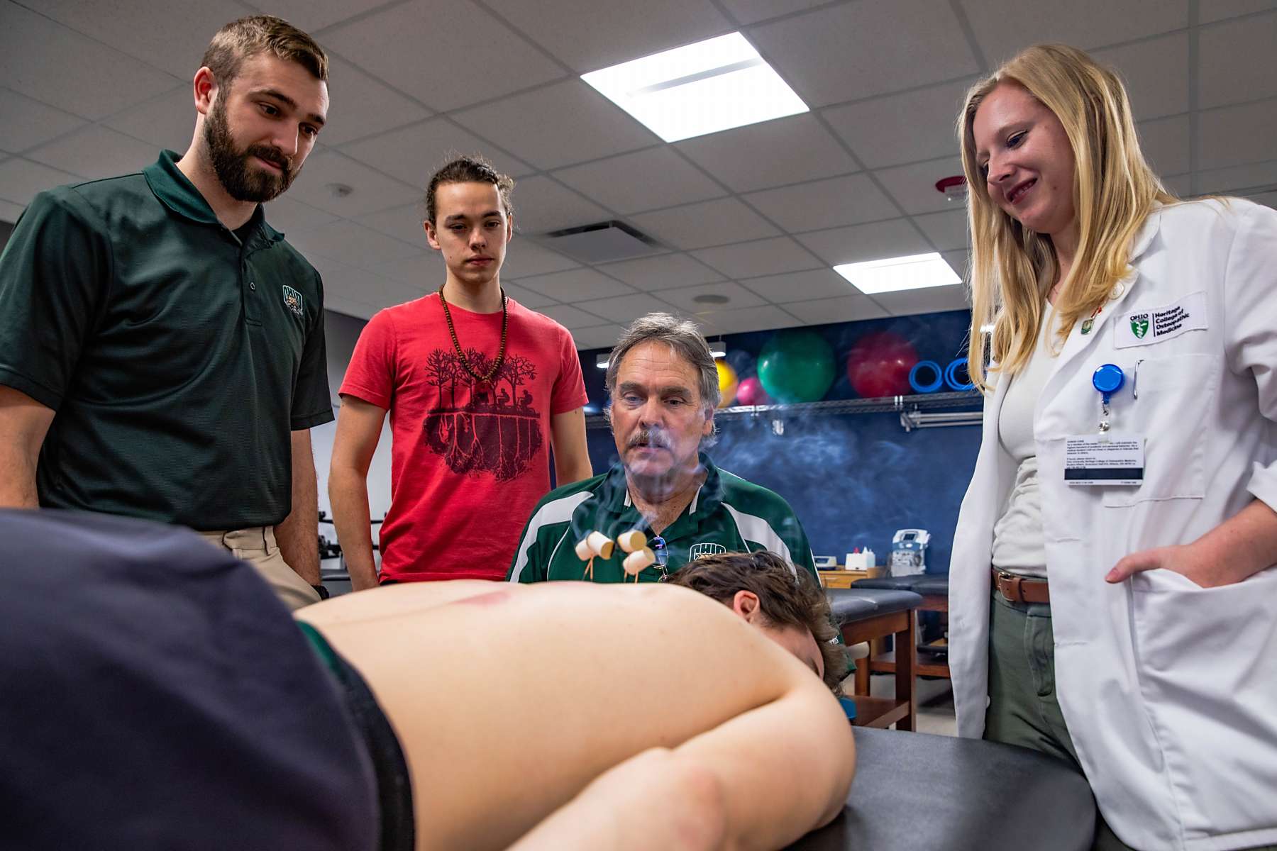 Medical students observe as a volunteer receives acupuncture treatment