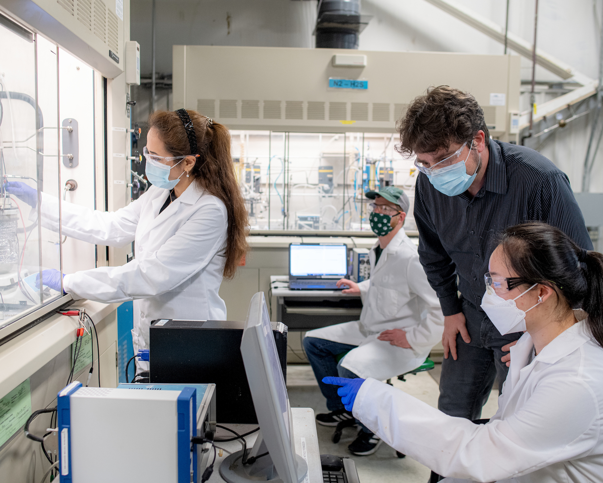 Marc Singer and three students wearing masks work in the lab facility