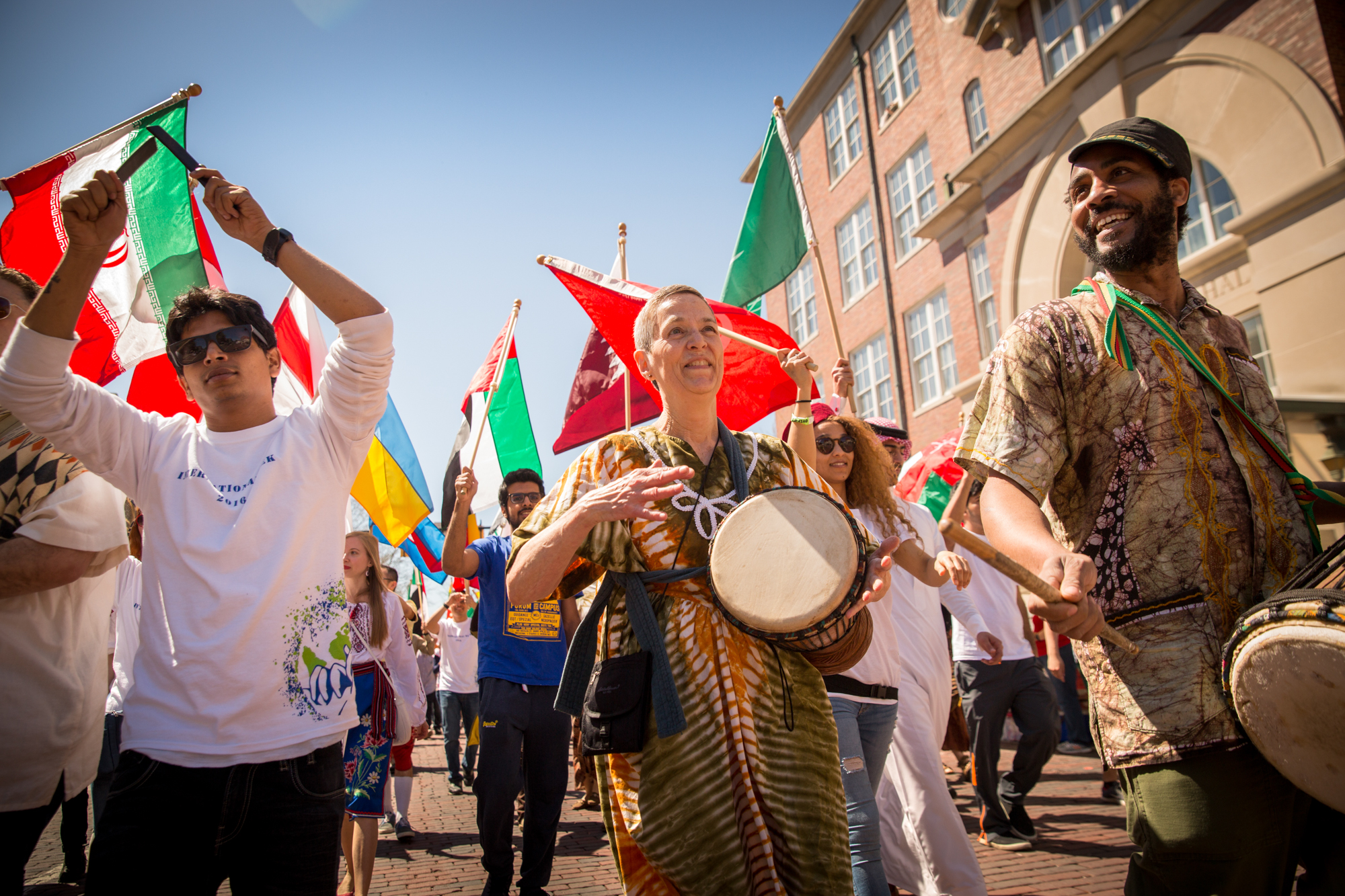 A diverse group of parade attendees with international flags makes their way down Court Street during International Street Fair