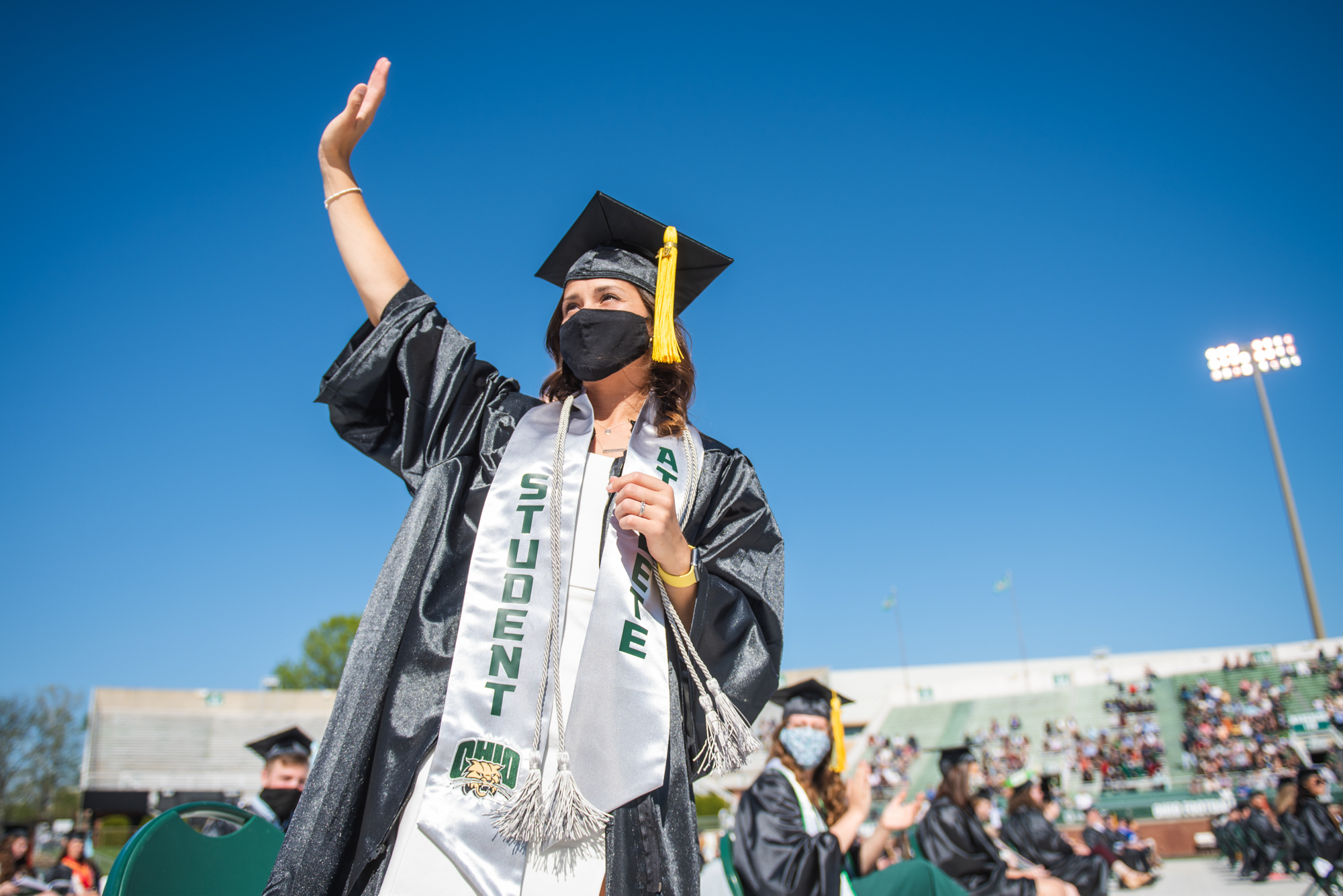 A graduating student waves to the crowd