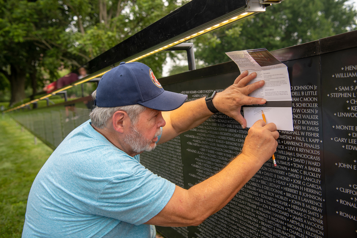Mark Curtis of Athens creates a rubbing of The Wall That Heals on the Ohio University campus