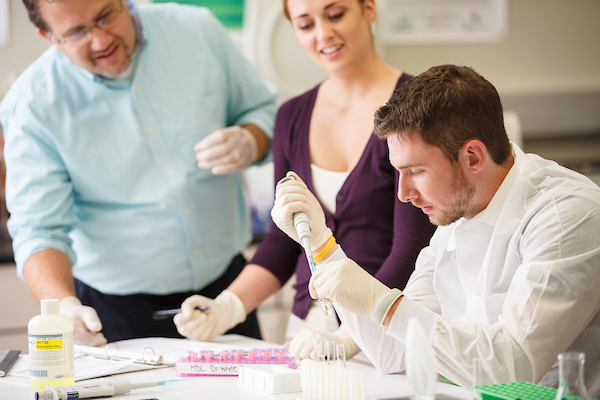 A teacher and two students work in the lab