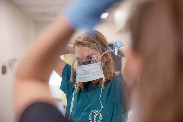 A med student ties her mask