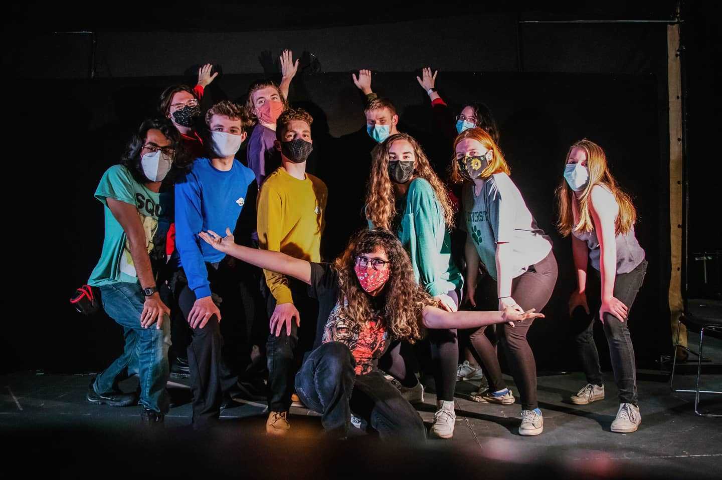 A group wearing masks poses for a picture on a stage 