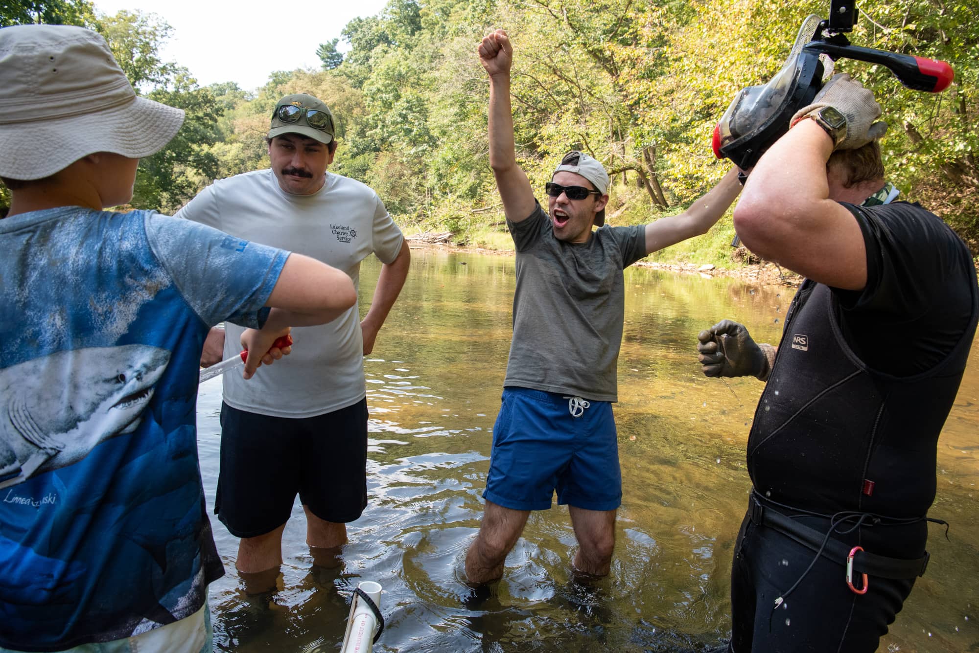 Arts and Sciences Associate Professor of Biology Viorel Popescu, Ph.D., center, reacts while collecting Eastern hellbender eggs from a wild nest in Pennsylvania.