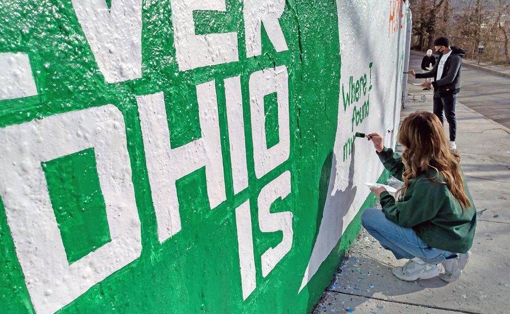 A photo of a student painting Forever OHIO on the graffiti wall.
