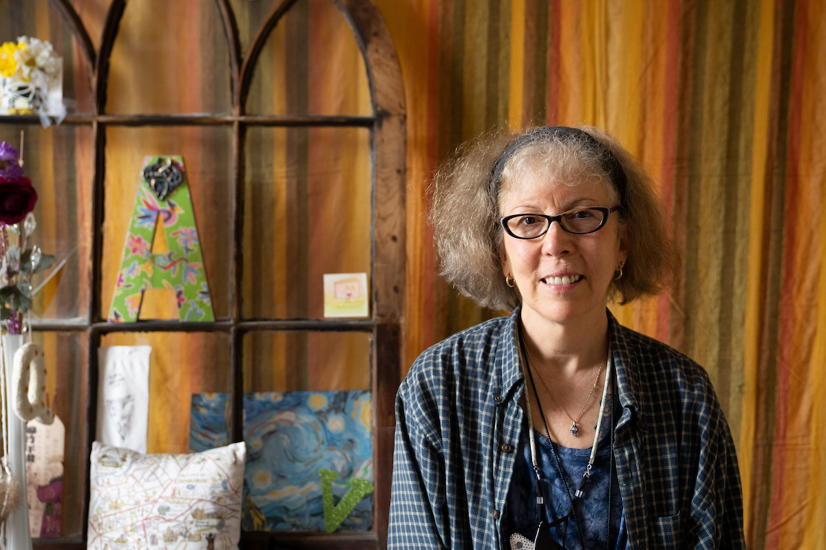 Julie Elman poses for a picture in her office, with a colorful curtain wall in the background