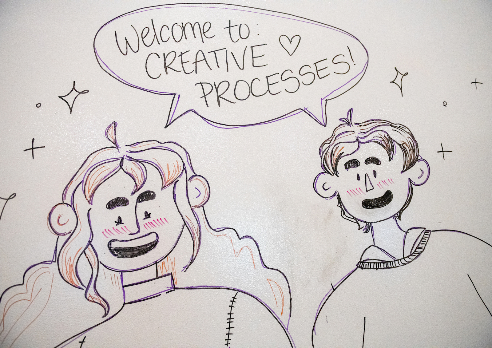 A drawing of two people with a speech bubble that says, "Welcome to creative processes!" 