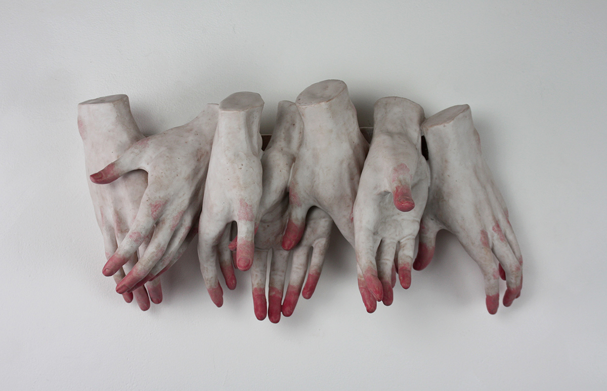 A row of eight sculpted hands with different-colored fingertips overlapping each other
