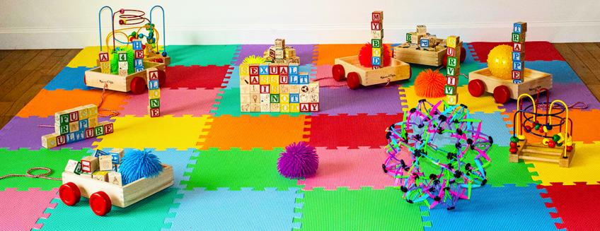 Variety of kids' blocks with text and other kids' toys arranged on a colorful carpet