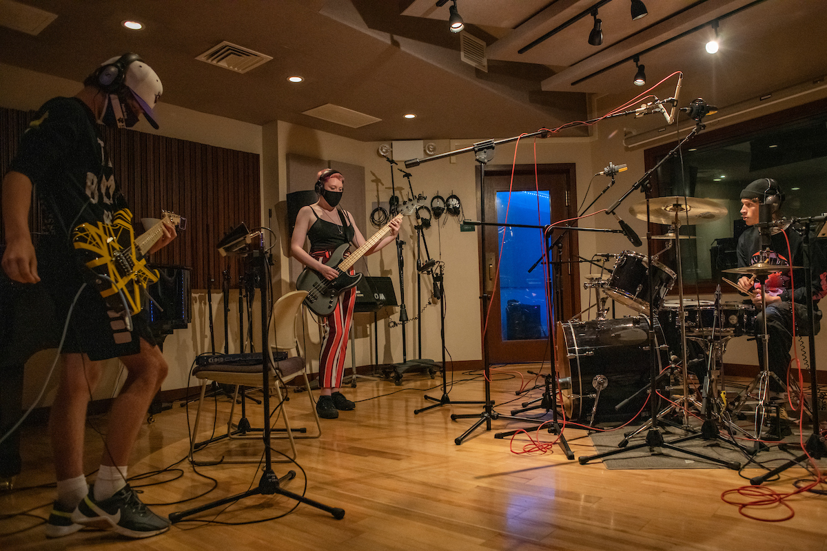 Students in a recording lab with guitars and drums.