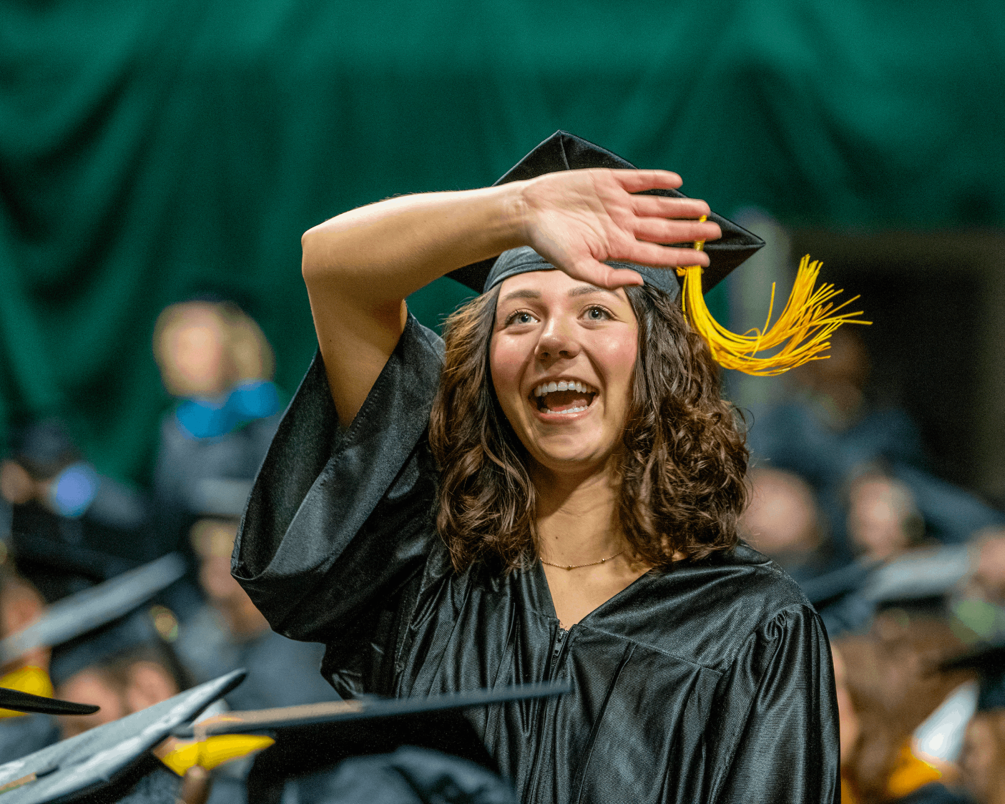 A graduate waves to a supporter at Fall Commencement.