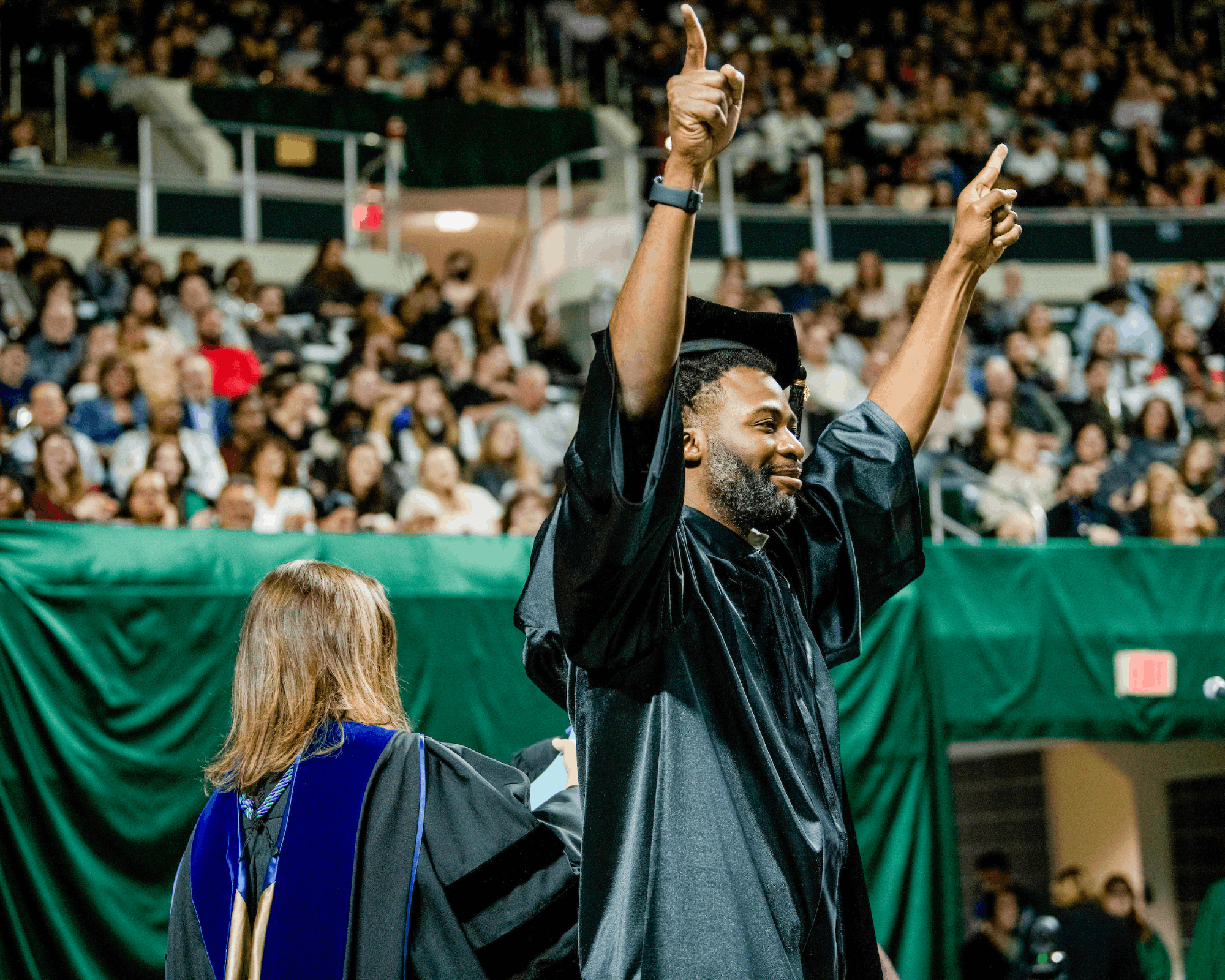 A graduate celebrates on stage at Fall Commencement.