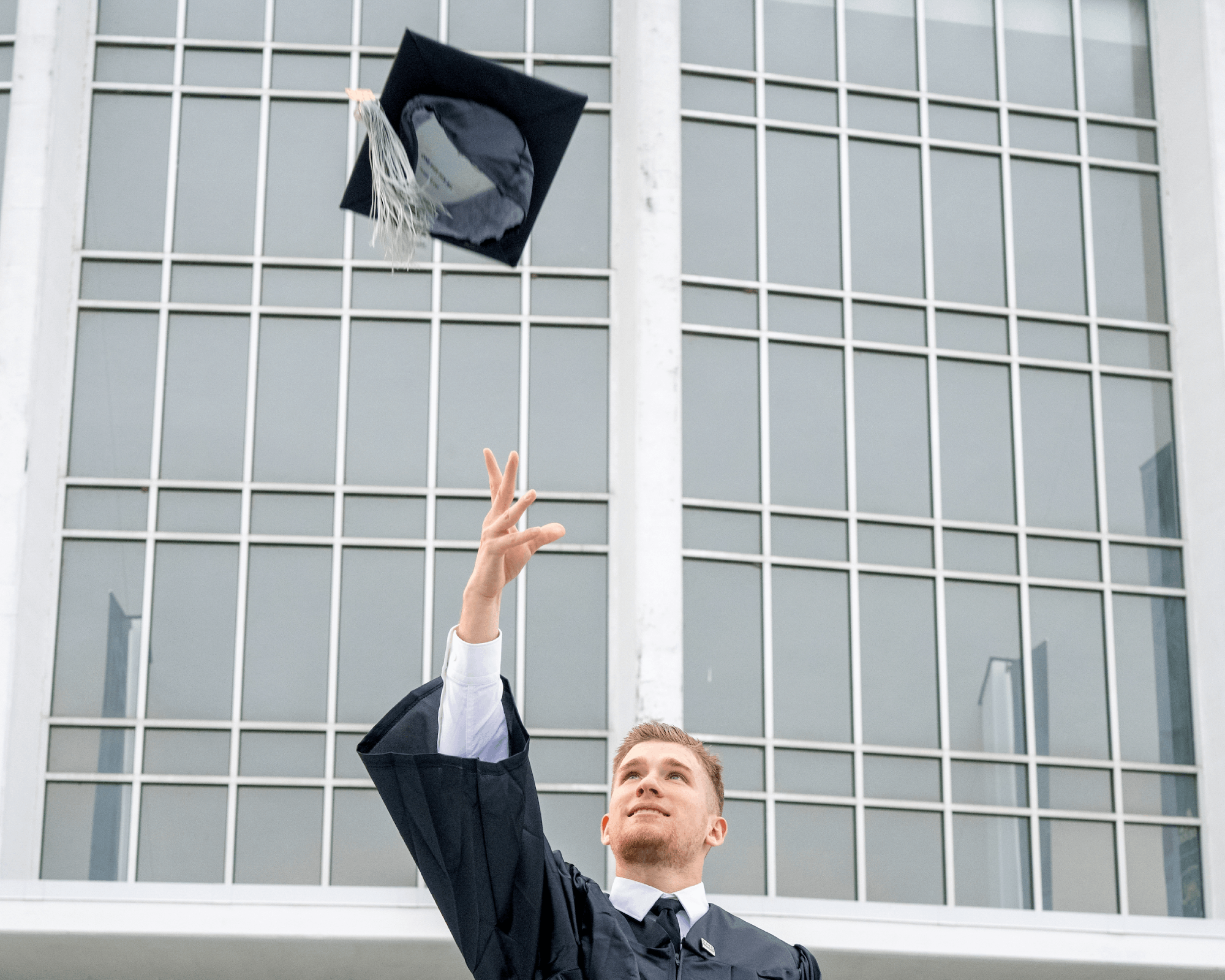 A graduate throws his cap in the air following Fall Commencement.