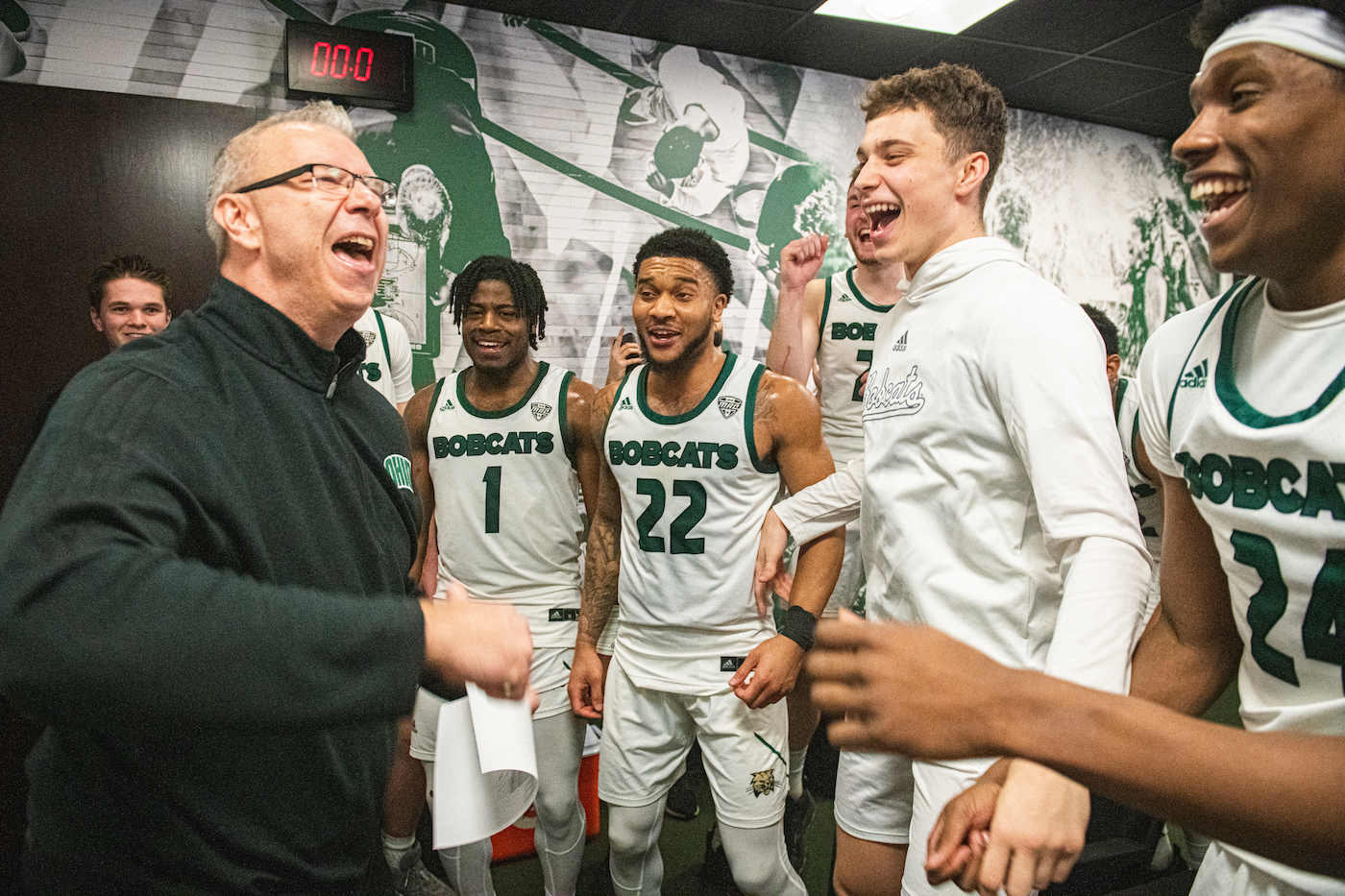 Head coach Jeff Boals and several basketball players are all smiles after a win