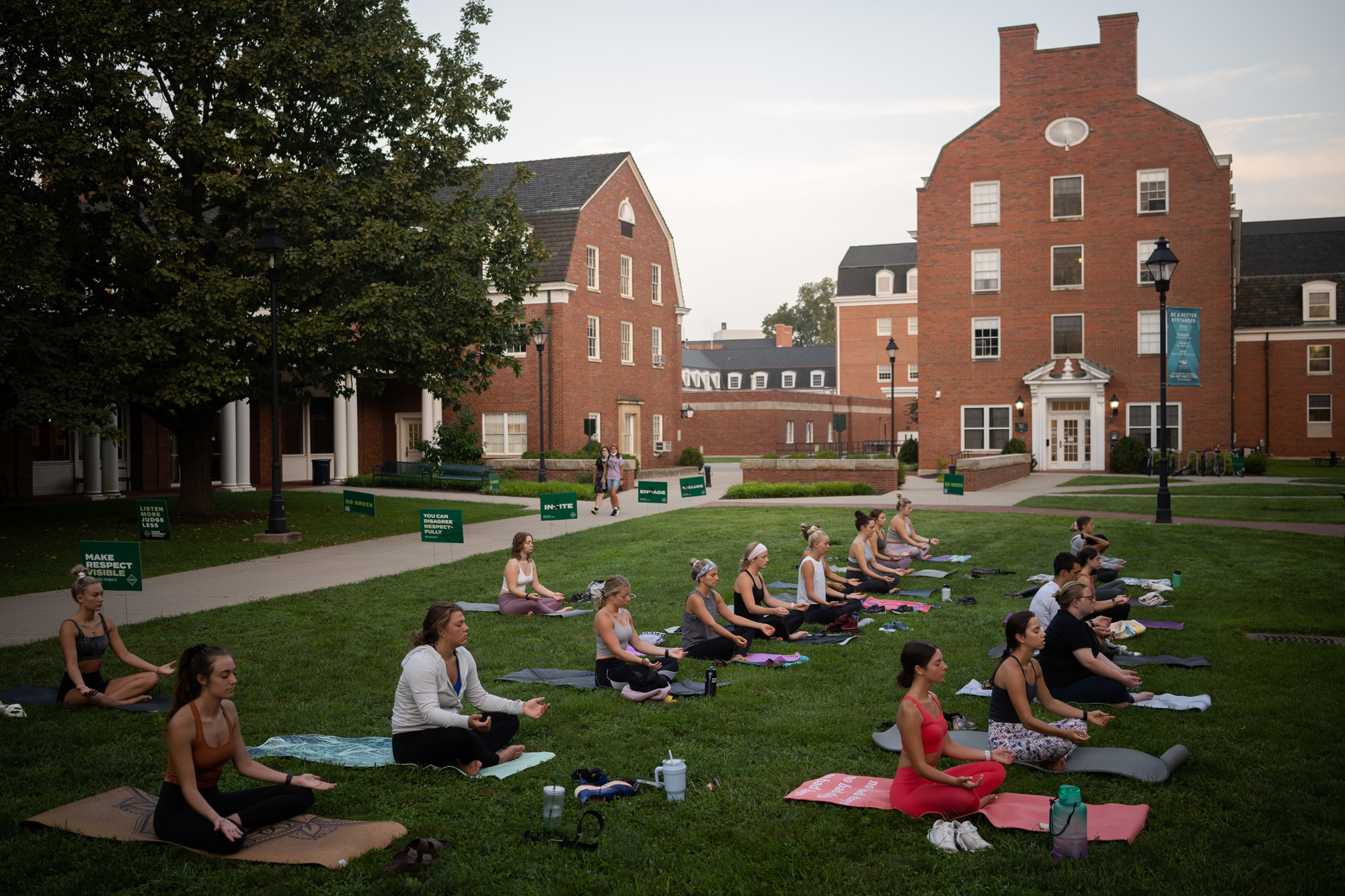 Rows of students practicing seated meditation on West Green during a Sunrise Yoga session