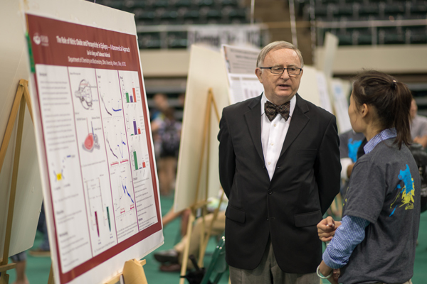 Tadeusz Malinski discusses research with a student on the floor of the Convo at the Student Expo in 2013. Photo by Ben Siegel
