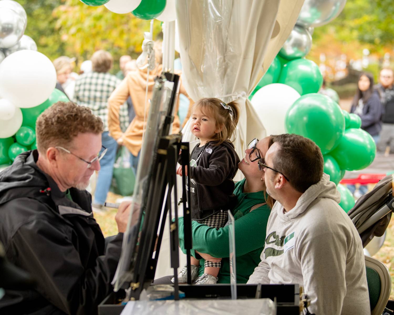 A child poses for a caricature during Homecoming festivities on College Green.
