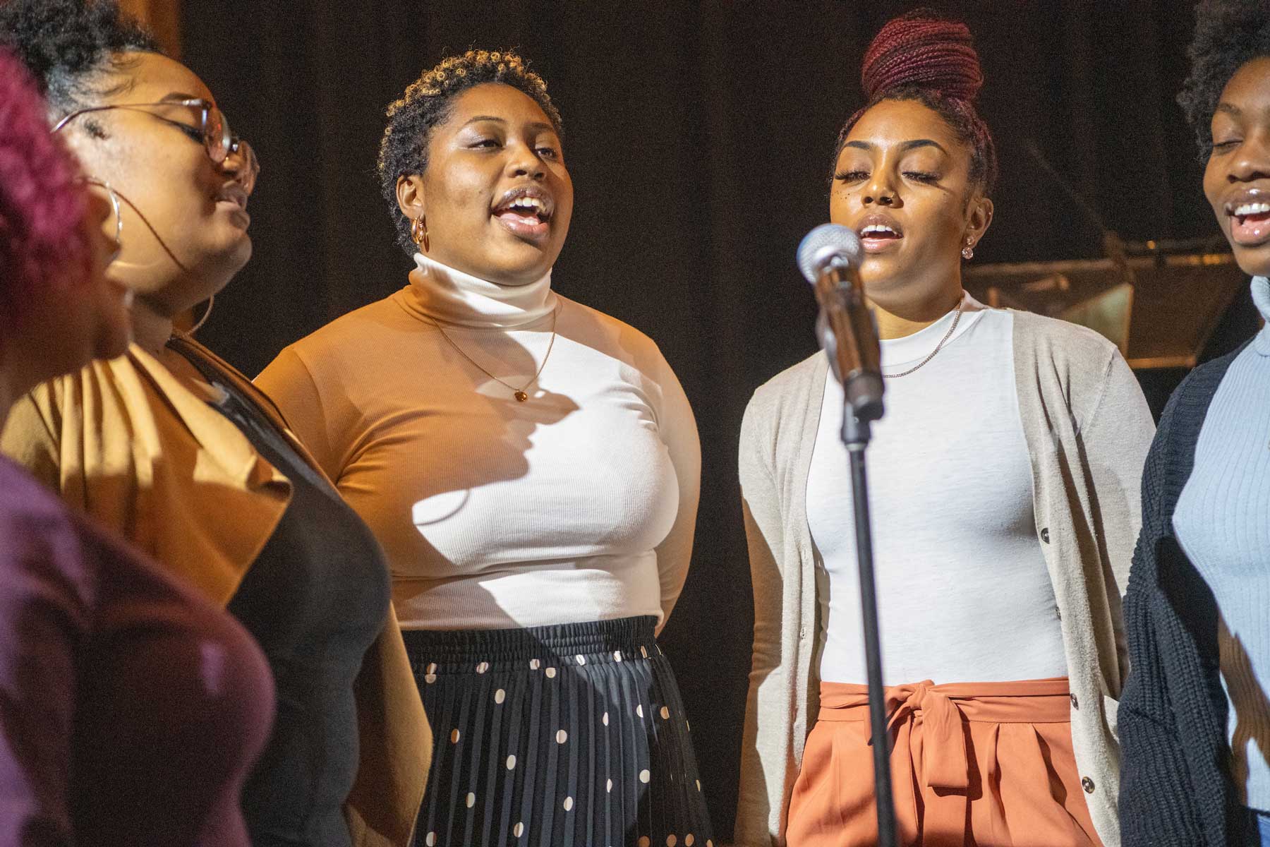 Photo of The Anointed Praise gospel choir performing in front of a microphone.