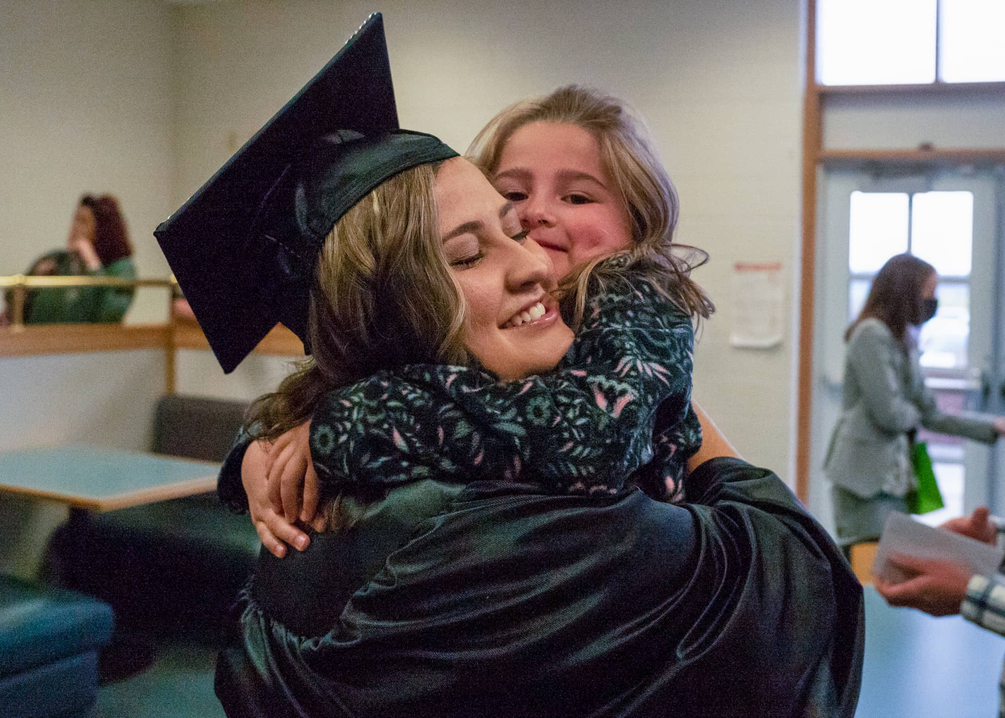 A graduate gets a hug following a graduation recognition ceremony on the Eastern Campus.