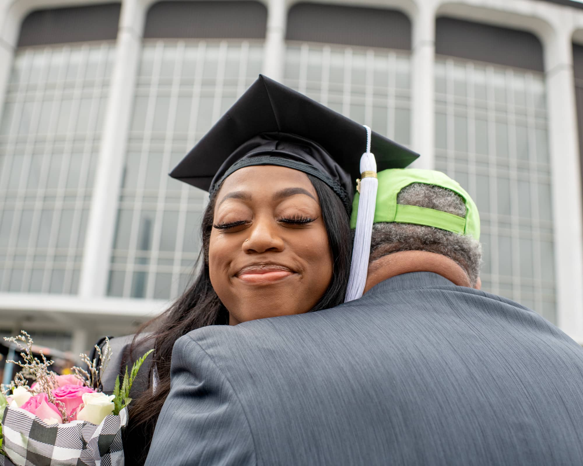 A student receives flowers and a hug following undergraduate commencement.