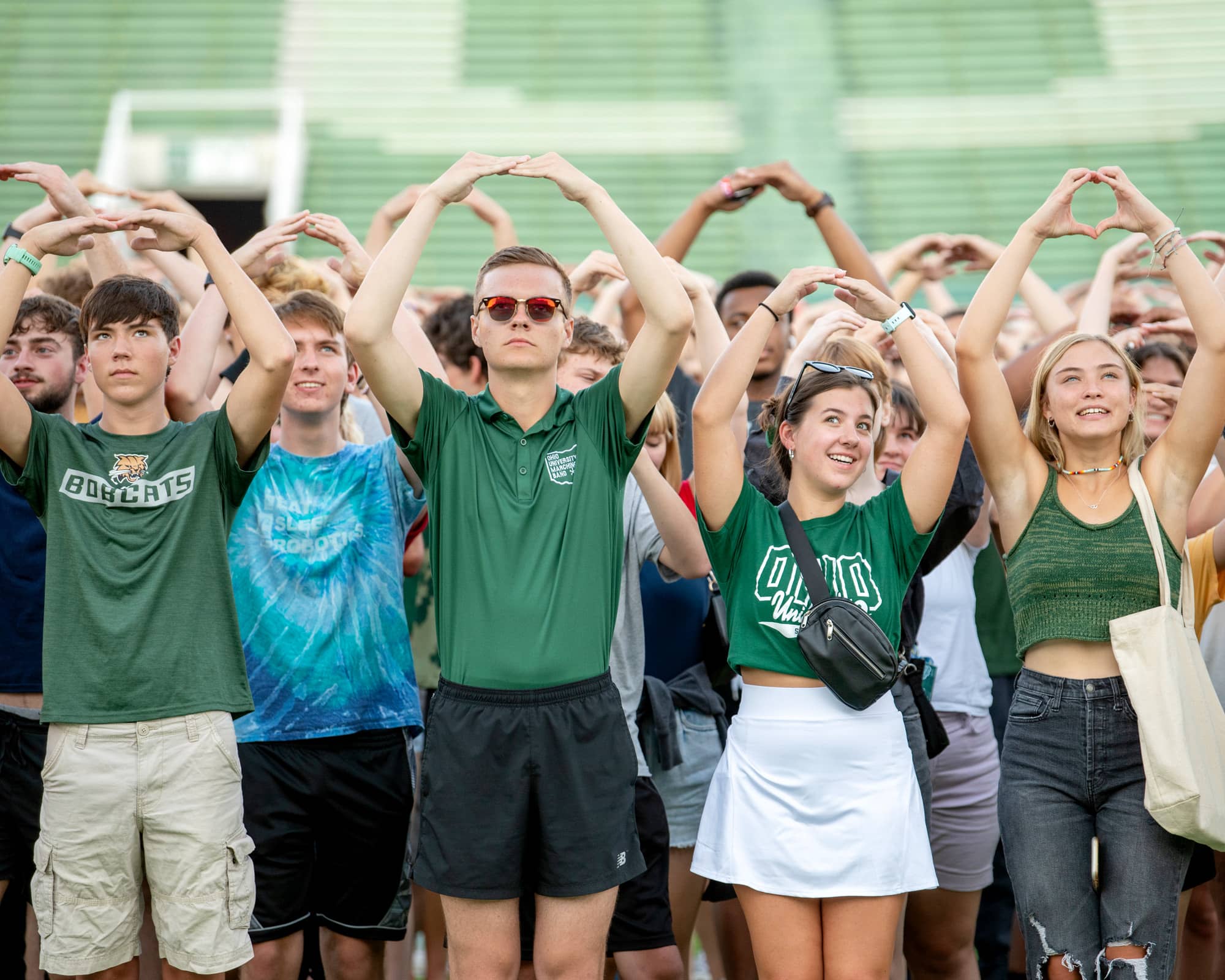 Students make the letter O with their arms during the class photo at Peden Stadium.