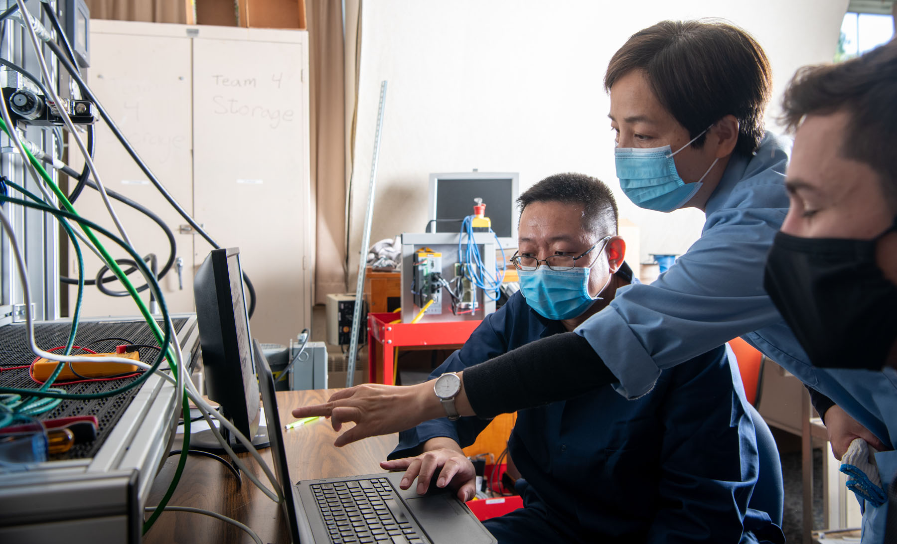 Three students review results of an experiement on a computer screen