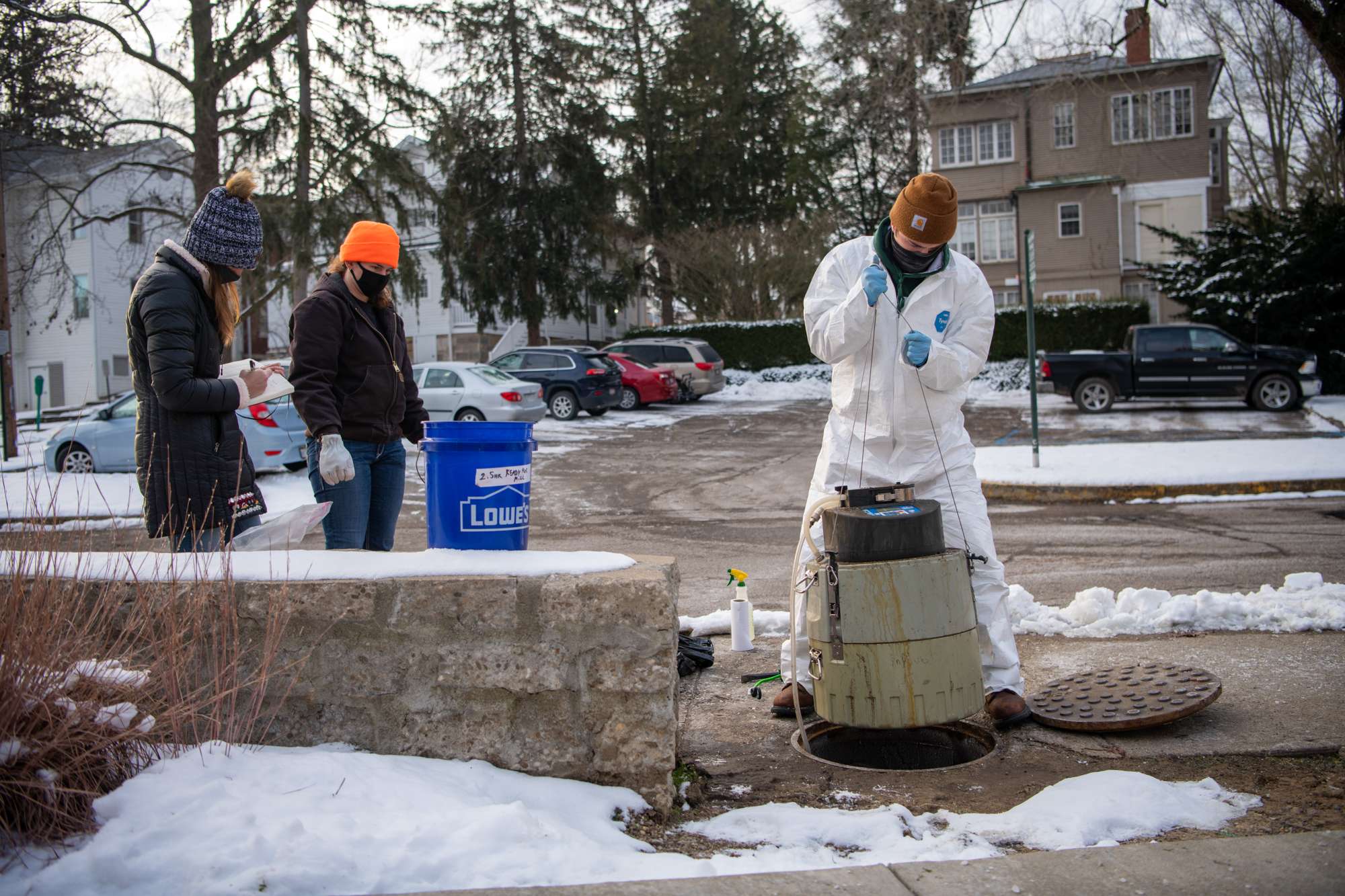 A piece of equipment used for wastewater moniotiring is retrieved from the sewer by a group of student researchers