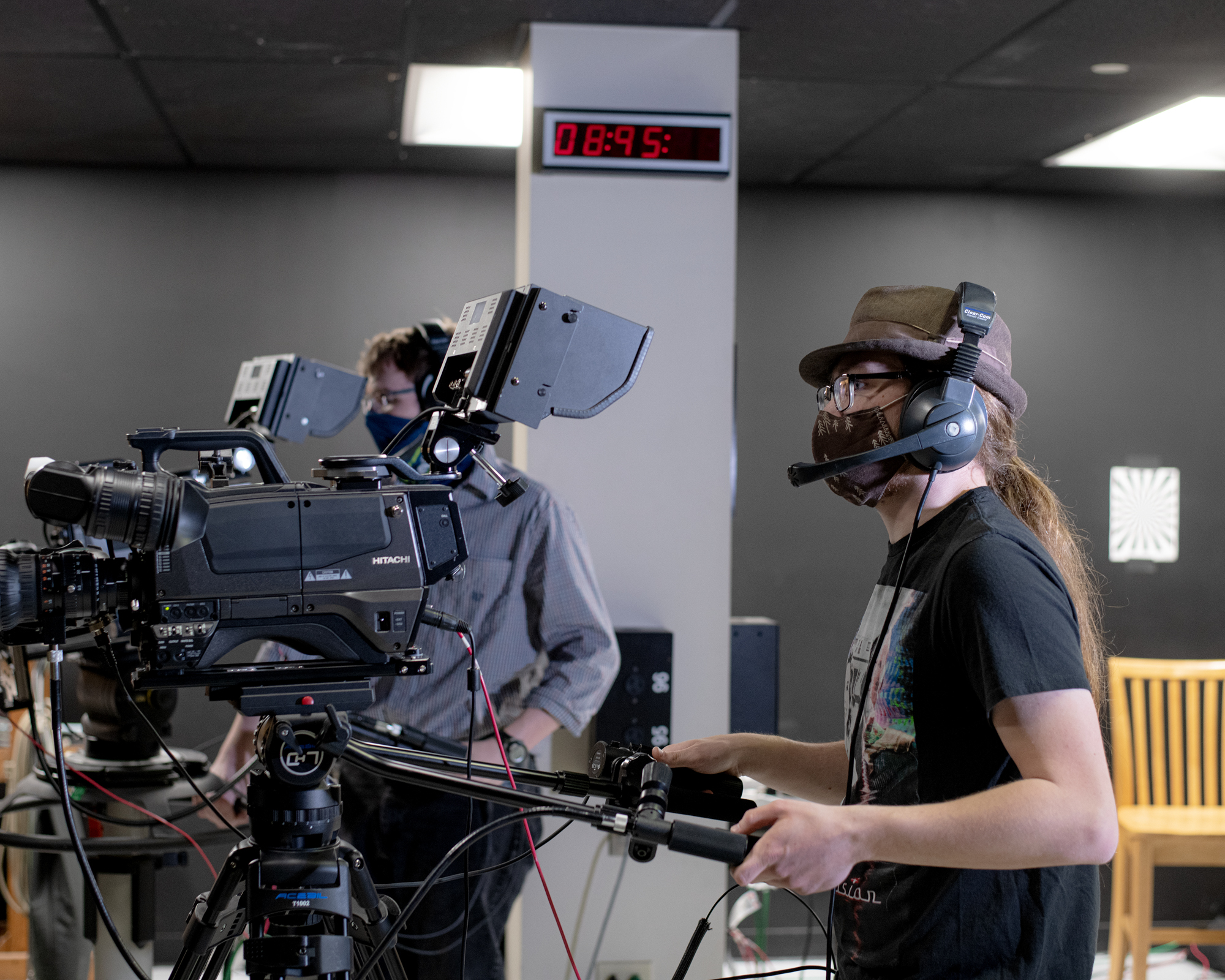 Two film students working behind cameras on a soundstage set