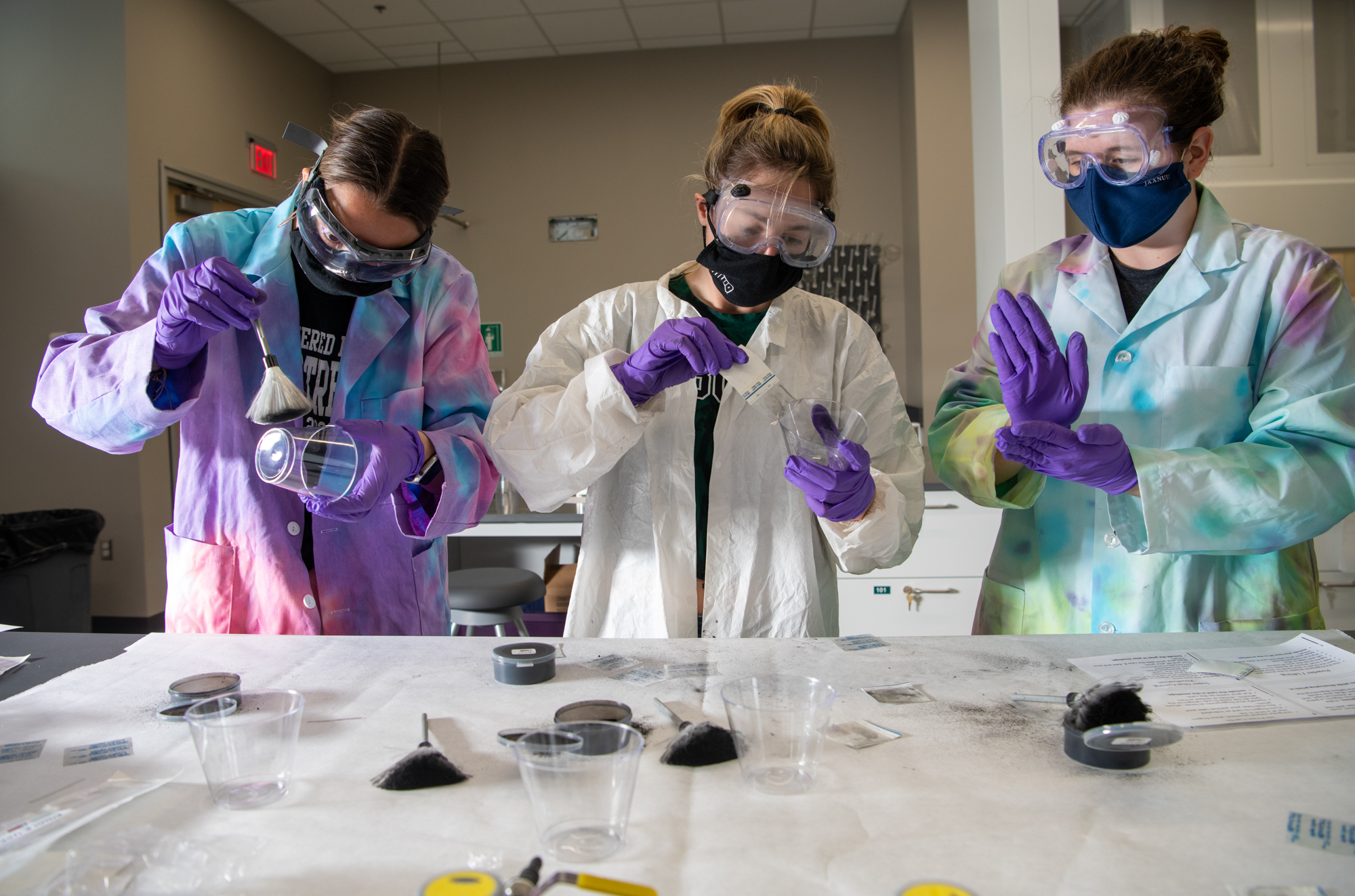 Forensics students in full laboratory attire working on fingerprint recovery