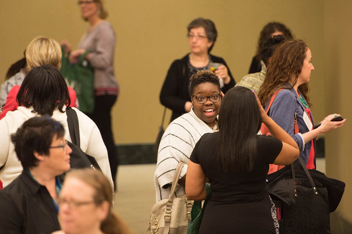 Attendees mingle between conference sessions and speak with conference sponsors