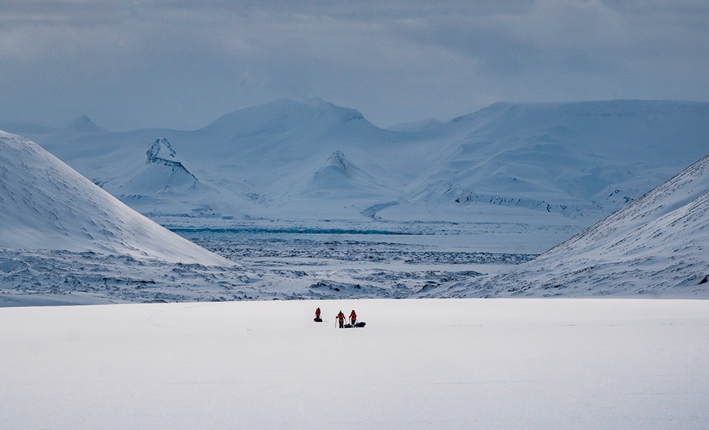 Three people walking in a tundra.