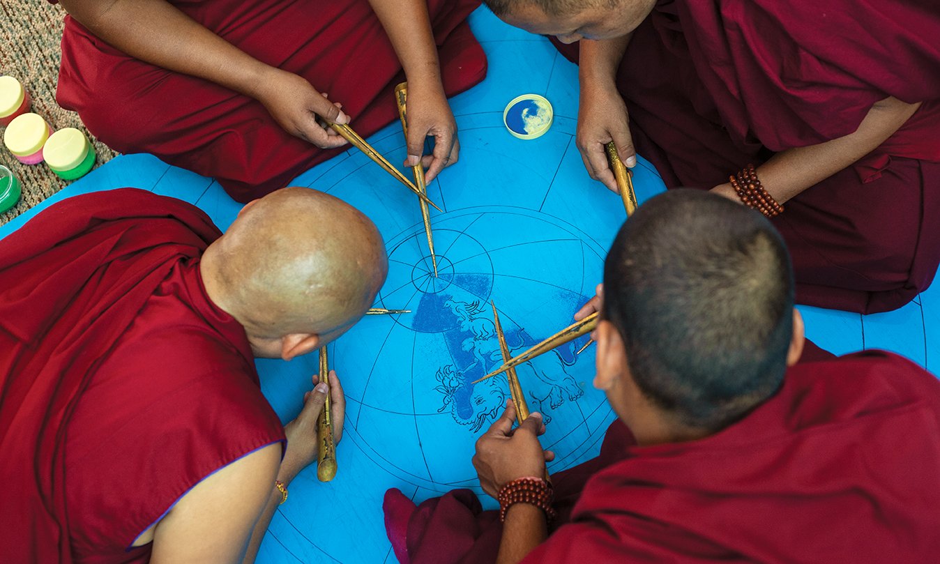 Buddhist monks work on drawing a mandala