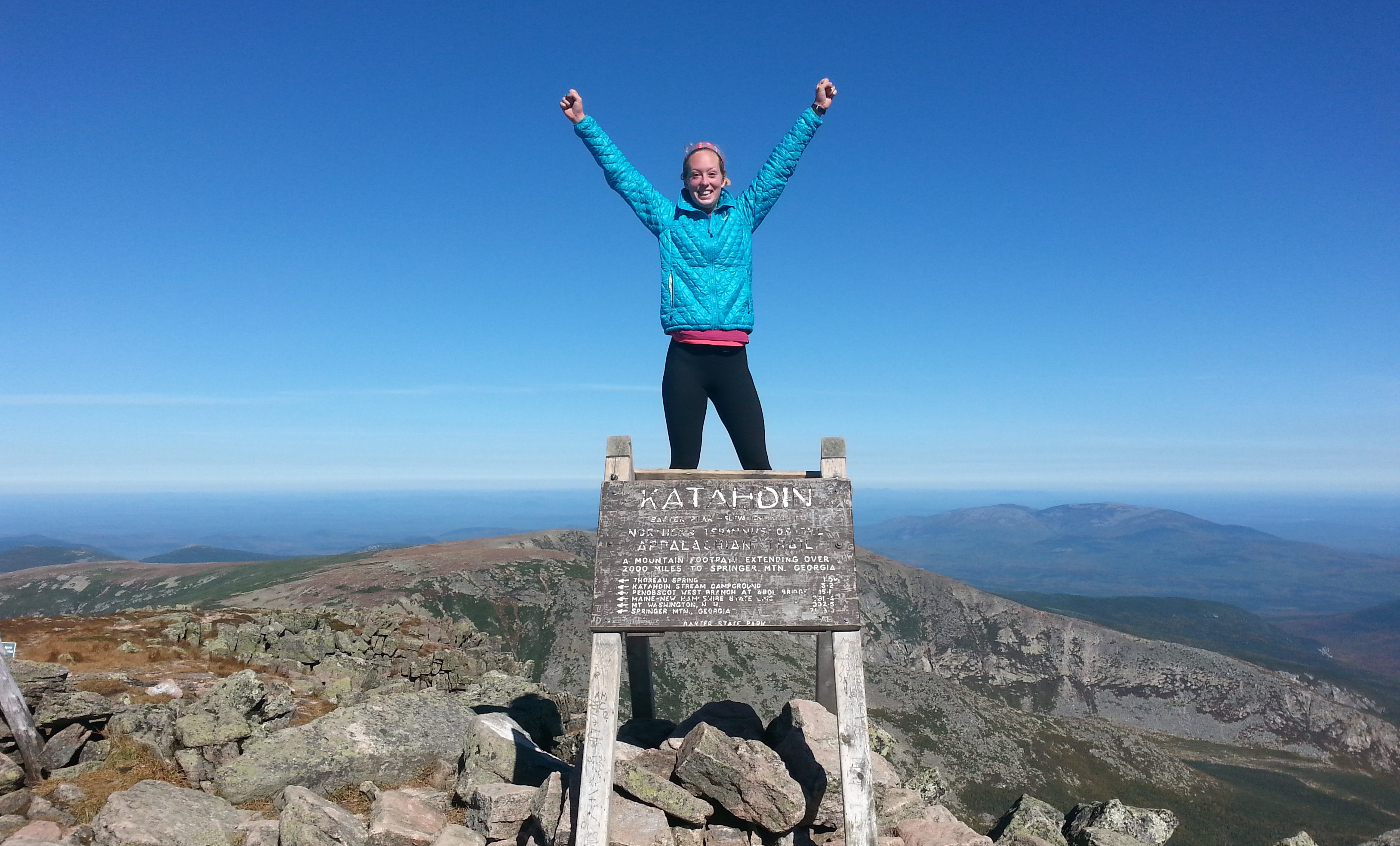 Kate Schmidlin standing triumpantly above a sign reading Mount Katahdin, Maine