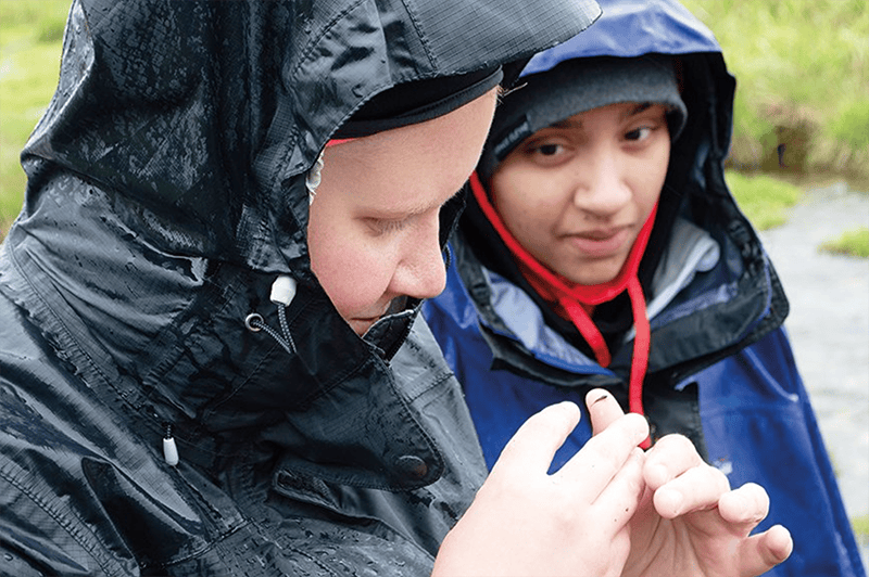 Madeline Peck (left) and Imani Evans observe a macroinvertebrate collected from (and returned to) a stream. near Black Tail Pond in Grand Teton National Park during a watershed field-research project.