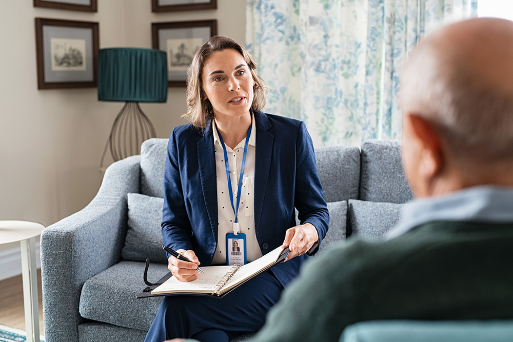 Social worker talking with senior citizen during home visit.