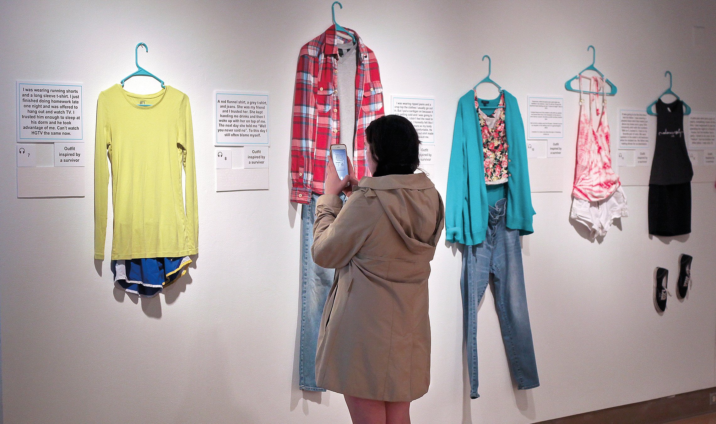 Student takes photos of clothing in an art gallery