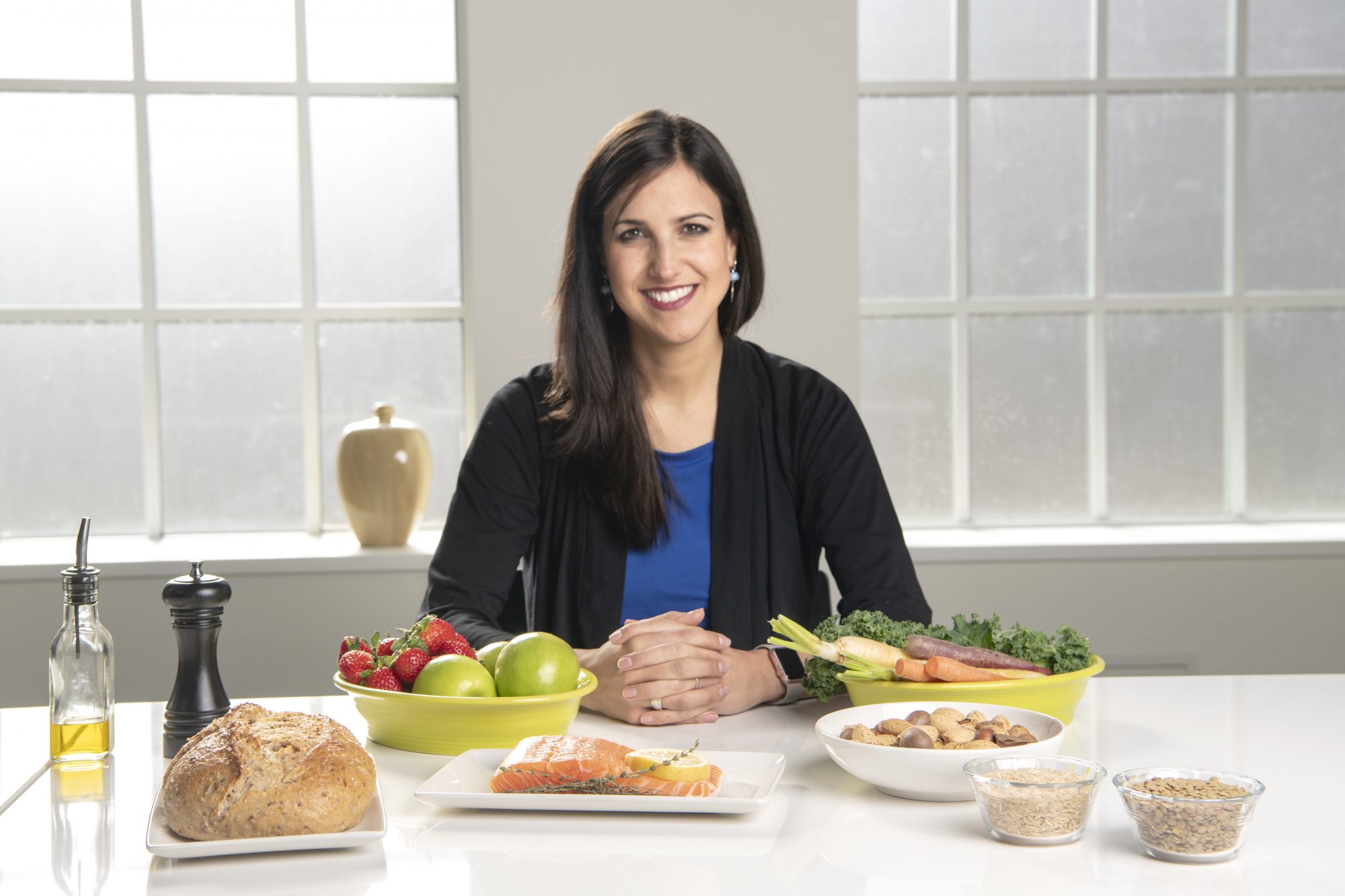 Woman sits at table with various food in front of her