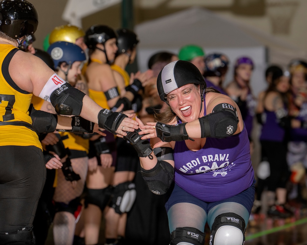 A roller derby athlete skates past cheering teammates